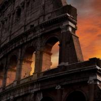Stone ruins of Roman Colosseum backed by red sunset