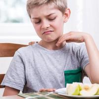 Child making a face at a cut up apple on a plate