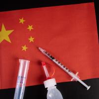 Red flag (of China) with medical syringe and bottle on top of it
