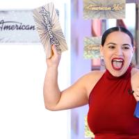 Person shouts joyfully, waving a card that says "American Idol"