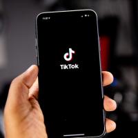 Hand holding a smart phone showing the TikTok icon