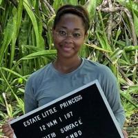 Person standing in a field holding a sign that says "Estate Little Princess"