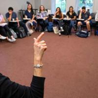 person teaching American Sign Language to a group in a circle