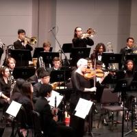 musicians playing their instruments on a stage, seated or standing behind music stands