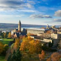 Cornell campus seen from above in autumn, with Cayuga Lake in the distance