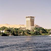 The Nile River passing a hotel, palm trees and a sandy hill