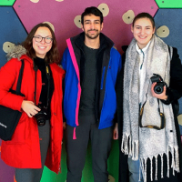 Three students holding camaras, colorful background
