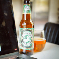 Beer bottle and glass by a computer