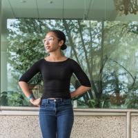 Dejah Powell ’18 outside Mann Library, with foliage visible in the window behind her