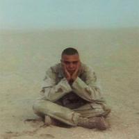 Marine soldier sitting cross-legged in the desert.
