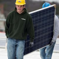 Workers walking with a solar panel