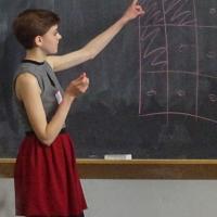  high school student giving presentation on chalkboard