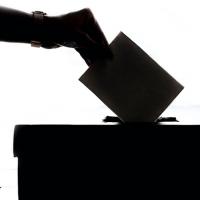  Silhouette of a hand putting a ballot on a box