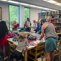 Alumni and families gather around a table with hyperbolic crochet examples and books