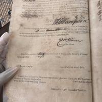 gloved hand holding an antique document