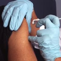  Gloved hands administer a shot to an upper arm