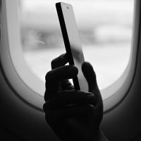 hand holding a cell phone frame by an airplane window