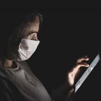  A woman wearing a mask using a touchscreen
