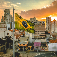  Brazilian flag with city and sunset in background