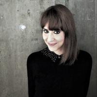  Valeria Dani - a woman in a black sweater before a gray, concrete background.