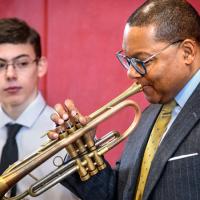 Wynton Marsalis showing a middle school student how to blow a trumpet