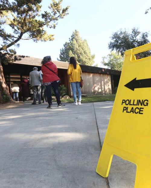 Yellow "polling place" sign and voters