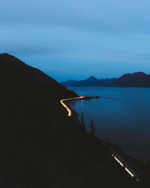 Highway with lights snakes between mountain and bay