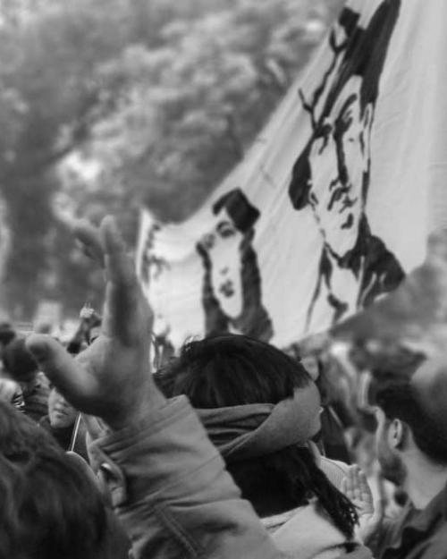 Black and white image of a rally; people around a flag