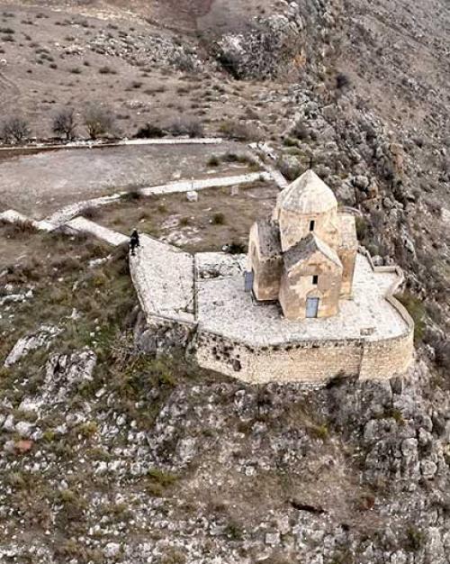 Ancient stone building in a rocky landscape, seen from above
