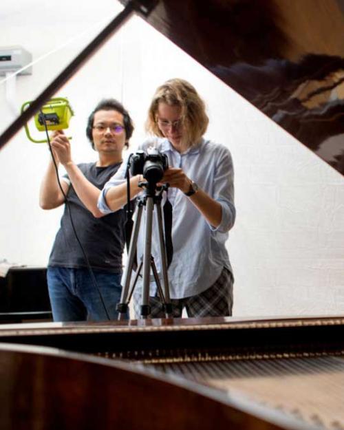 two people taking photos of a piano