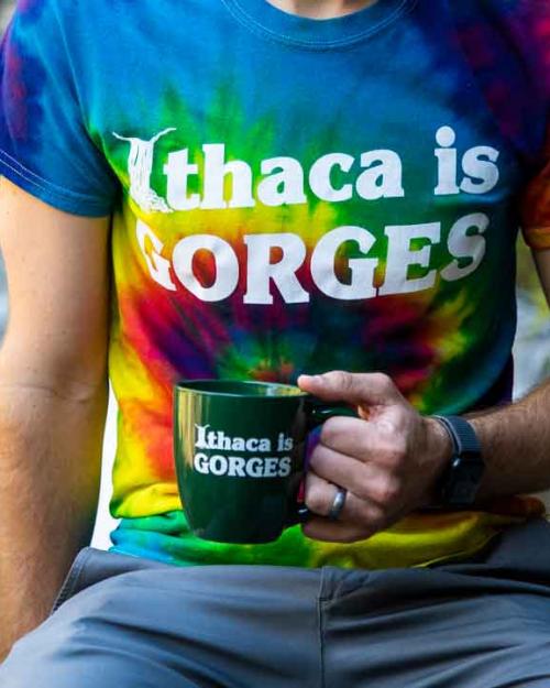 a person wearing an Ithaca is Gorges tshirt with mug and water bottle