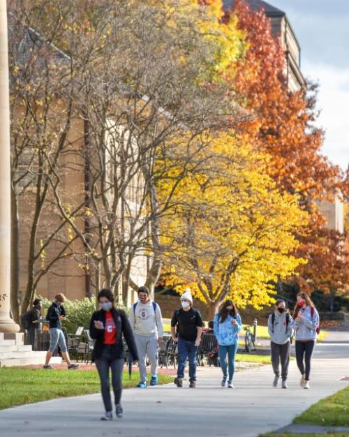 Students walking in front of Goldwin Smith Hall, with trees showing Autumn colors