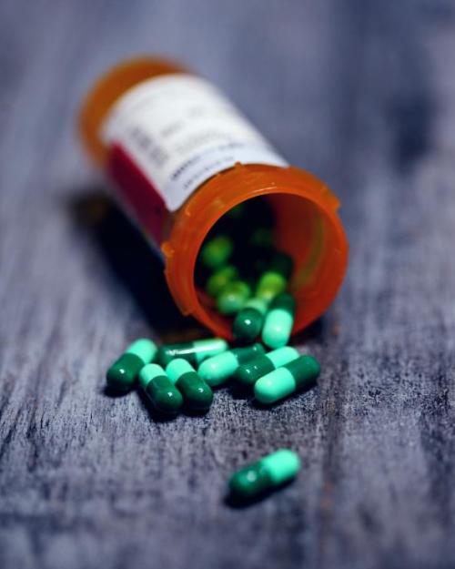 Orange pill bottle, spilling green pills