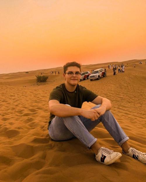 student sitting on sand dune