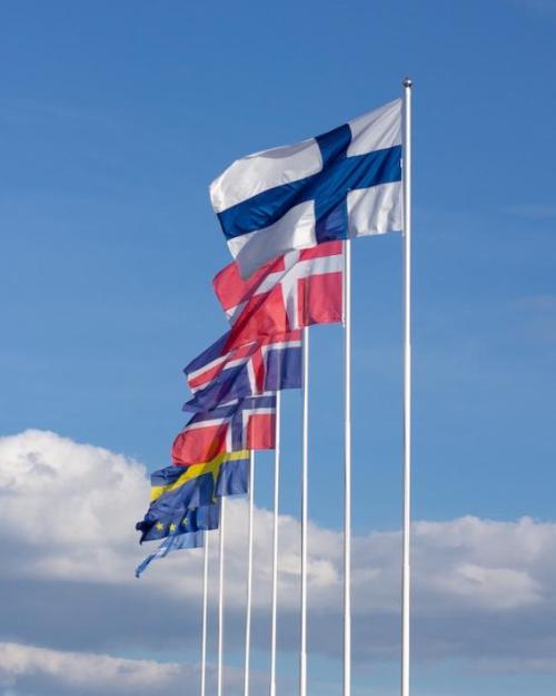 Seven flags on poles against a blue sky