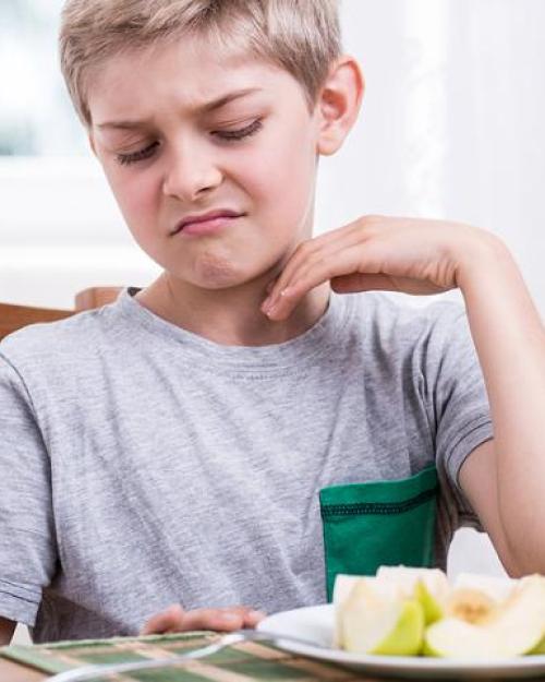 Child making a face at a cut up apple on a plate