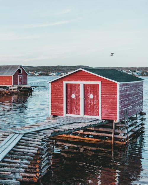 		Two red shacks on log platforms in a bay
	
