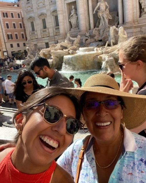 two women smiling in front of fountain