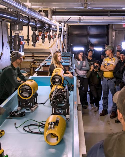 		Group of people in an equipment room, a table of parts
	