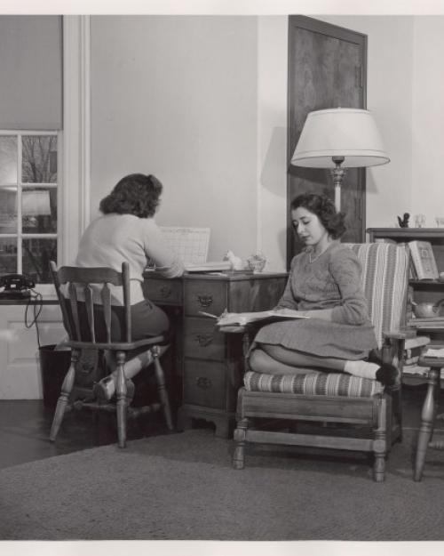 Black and white historic image of two people studying quietly in a neat room