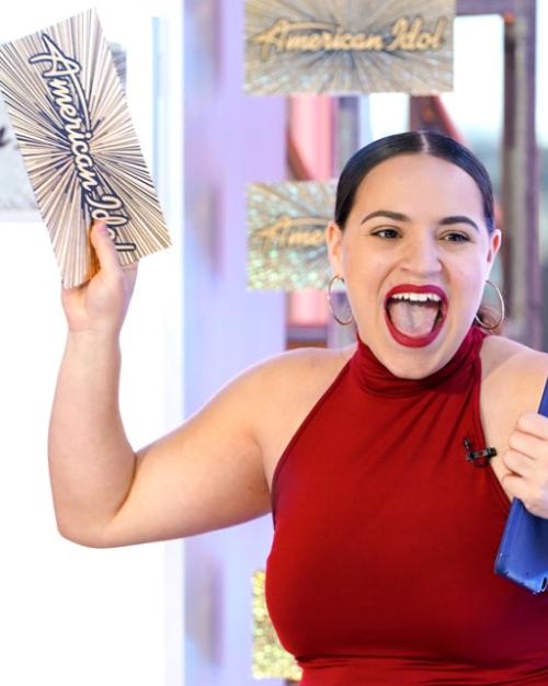 Person shouts joyfully, waving a card that says "American Idol"