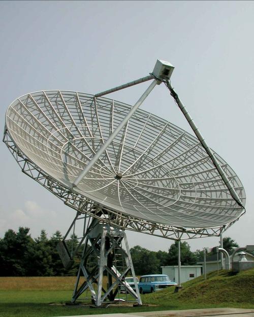 A telescope with a big metal disk with a giant tripod of metal protruding from its rim.