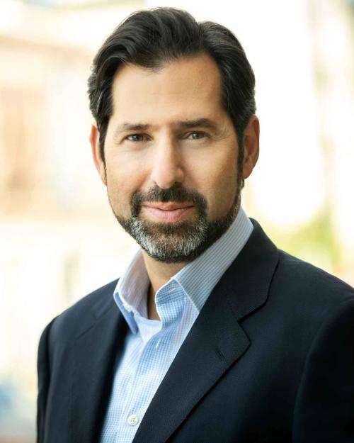 A headshot of David Folkenflik, with black short hair and a salt and pepper beard and mustache, wearing a suite jacket.