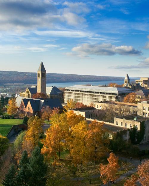 Cornell campus seen from above in autumn, with Cayuga Lake in the distance