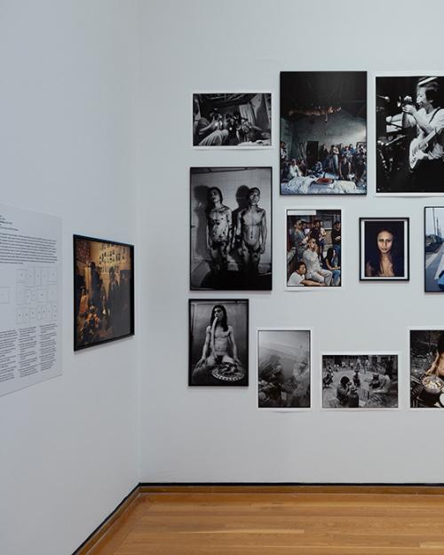 Images, most of them black and white, hung on a white museum wall