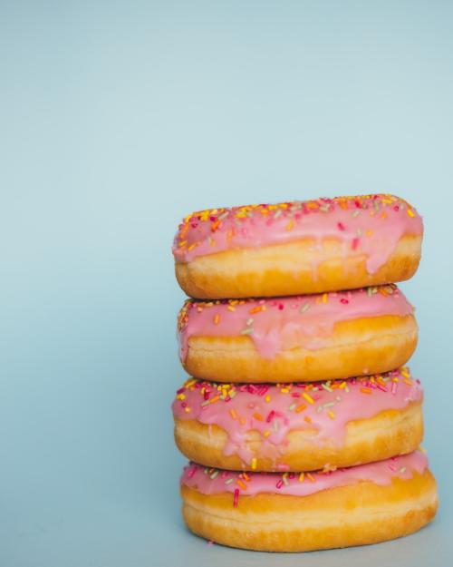 		Four donuts in a stack: frosted pink, covered with sprinkles
	