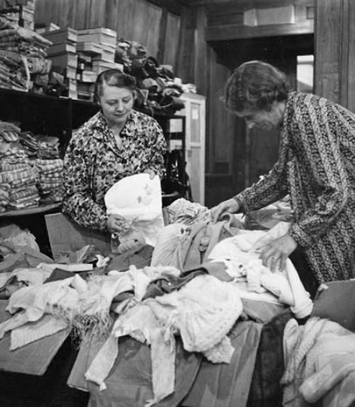  Two women sorting a big box of used clothing