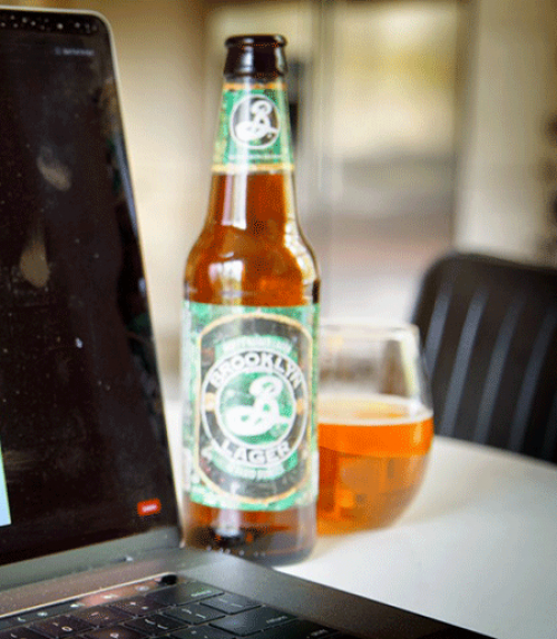 Beer bottle and glass by a computer