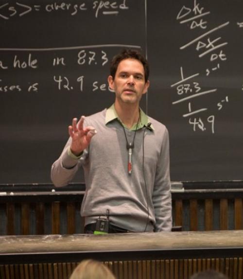 Professor giving lecture in-front of chalkboard with equations