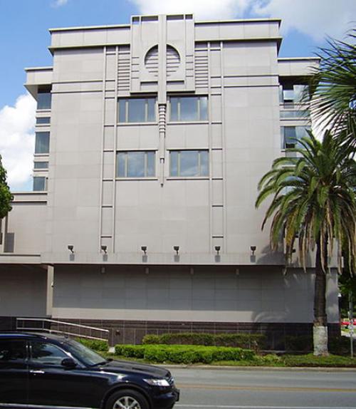 Grey concrete building, palm trees, blue sky